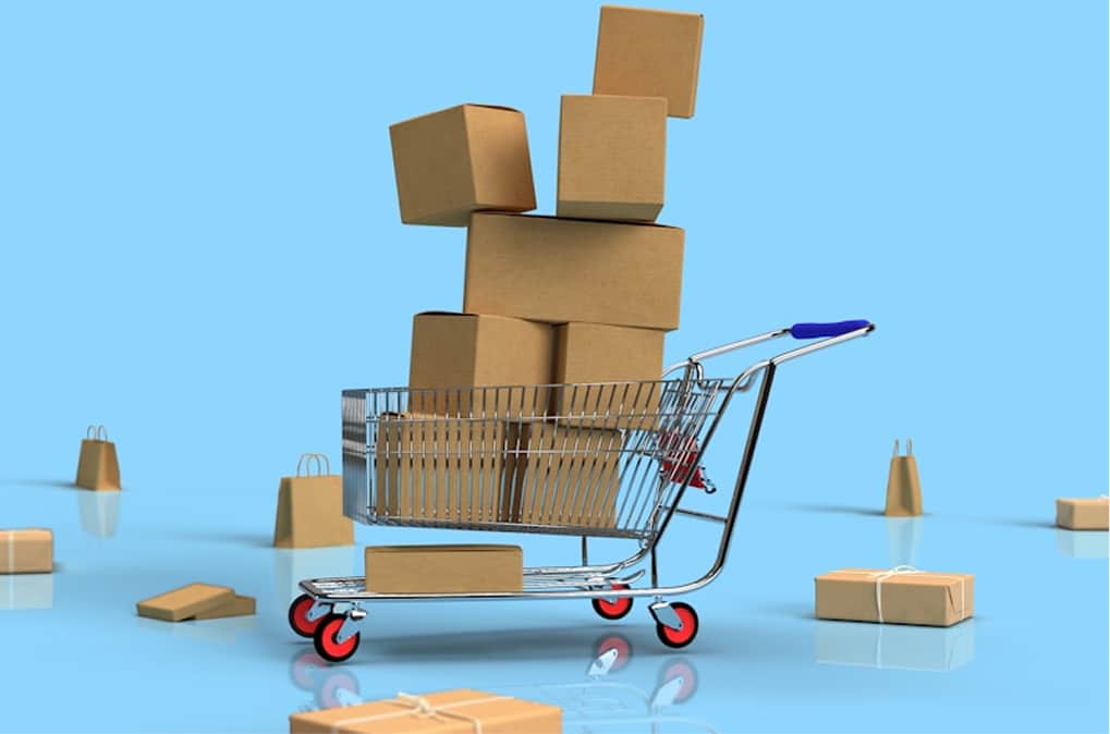 Carrito de compras lleno de cajas de cartón sobre un fondo azul.